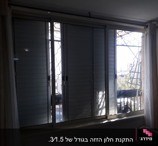 חלון אלומיניום עם תריסים סגורים ומעקה חיצוני